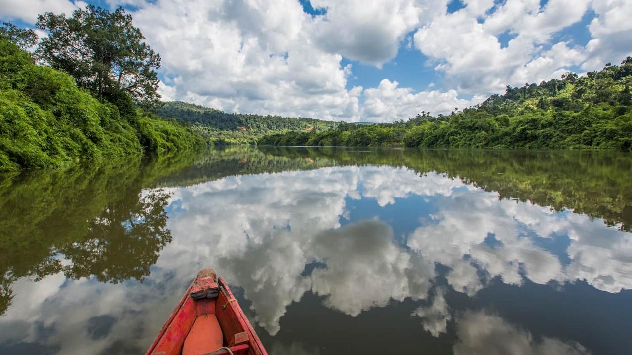 Red canoe on river reflecting clouds at Rainbow Lodge